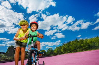 Big brother help little boy ride a small bicycle cute photo of siblings posing together