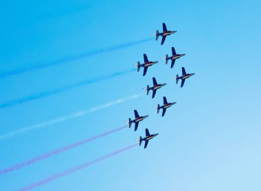 Squadron of planes fly with color trail in blue red white lines over clear sky in colors of USA Holland or France