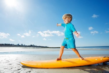 Handsome blond boy stand on the surfboard learning balance practicing surfing before going to ocean