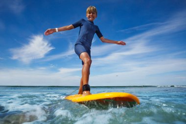 Young boy stand on the surf board smiling balancing with hands photo in the water