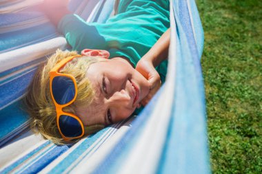 Happy smiling young boy lay in hammock close portrait turning head up and smile