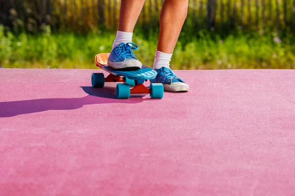 Close-up of the legs of a child riding skateboard on the color surface of a skatepark