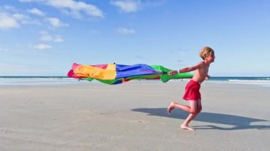 boy run with a colorful kite over the sea and beach, action motion dynamic concept
