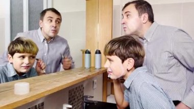 Dad and the son have fun in the bathroom shaving together