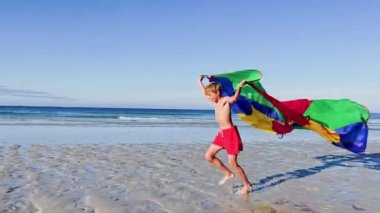 boy run with a colorful kite over the sea and beach, action motion dynamic concept