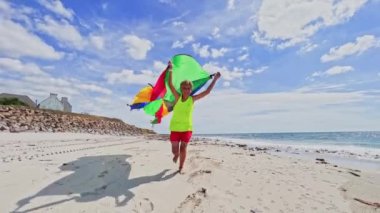 boy run with a colorful kite over the sea and beach, action motion dynamic concept