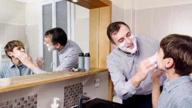 Dad and the son have fun in the bathroom shaving together