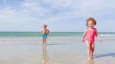 Group of children two boys with little girl  having fun running on the sand beach