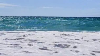 Sea waves surf on the beach during summer day with splashes 