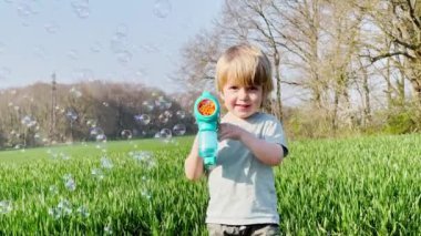 Portrait of a laughing blond happy boy at field in spring 