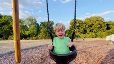 Çocuk parkında salıncakta sallanıyor. 