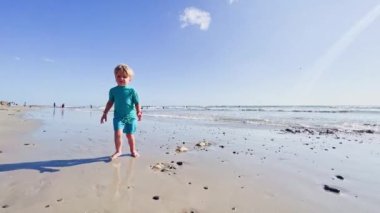 Happy little blond boy running  on the sand beach