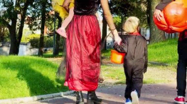 Cadılar Bayramı 'nda annelerinin ve bir grup çocuğun kostümlü hallerinin arkasında koca balkabaklı şeker kovası duruyor. 