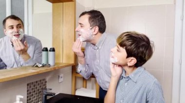 Dad and the son have fun in the bathroom shaving together