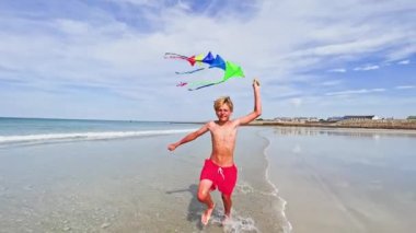 boy run with a colorful kite over the sea and beach, action motion dynamic concept