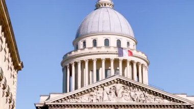 Fransa, Paris 'teki Pantheon binasının durağan manzarası mavi gökyüzünde Fransız bayrağına odaklanmış durumda.