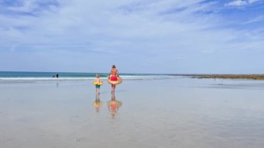 Two happy kids boys with inflatable toy buoys  having fun running on the sand beach