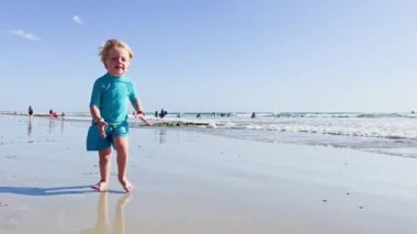 Happy little blond boy running  on the sand beach