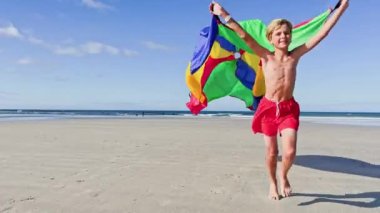 boy run with a colorful kite over the sea and beach, action motion dynamic concept