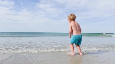 Happy little blond boy  on the sand beach