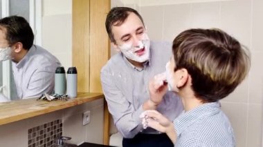 Baba ve oğlu banyoda birlikte tıraş olurken eğleniyorlar.