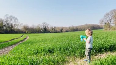 Portrait of a laughing blond happy boy at field in spring 