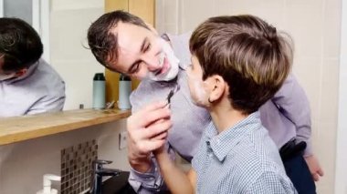 Dad and the son have fun in the bathroom shaving together