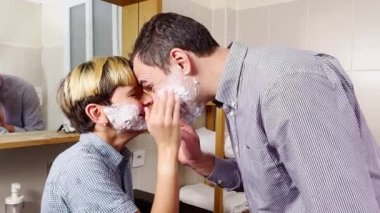 Dad and the son have fun in the bathroom shaving together