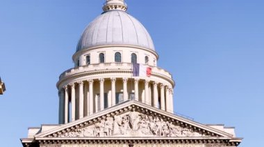 Fransa, Paris 'teki Pantheon binasının durağan manzarası mavi gökyüzünde Fransız bayrağına odaklanmış durumda.