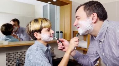 Dad and the son have fun in the bathroom shaving together