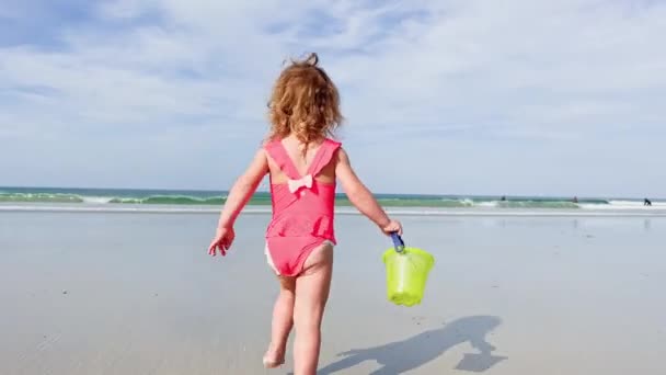 Schönes Kleines Kaukasisches Mädchen Läuft Mit Plastik Spielzeugeimer Sommerstrand Über — Stockvideo