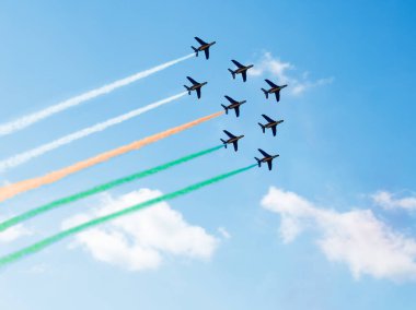 Squadron of planes fly with color trail lines of India or Cote d'Ivoire over clouds and clear sky