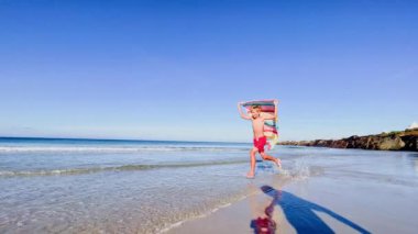 boy run with a colorful kite over the sea and beach, action motion dynamic concept