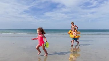 Group of children two boys with little girl holding inflatable toy buoys  having fun running on the sand beach
