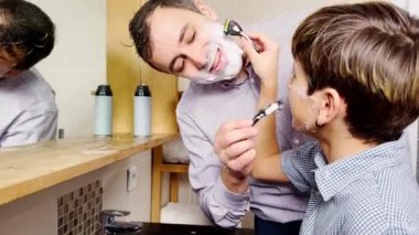 Dad and the son have fun in the bathroom shaving together