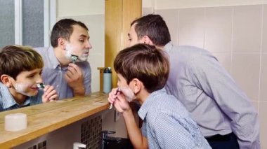 Dad and the son have fun in the bathroom shaving together