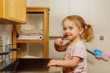 Kıvırcık bir kızın yakın portresi banyoda diş fırçasıyla diş fırçası.