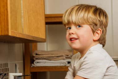 Banyoda gülümseyen sarışın çocuğun portresi.