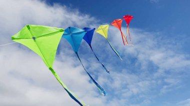 Group of many beautiful color kites fly on the string over blue sky with clouds