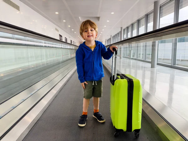 Liten Pojke Stå Flytta Gångväg Flygplatsen Med Grönt Bagage Resväska — Stockfoto