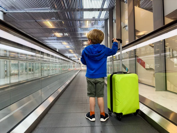 Liten Pojke Stå Flytta Gångväg Flygplatsen Med Grönt Bagage Resväska — Stockfoto