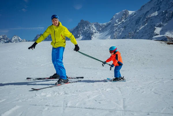 スキースロープのインストラクターは 両方のポールを保持するためにスキーする小さな子供を教える下り坂を滑ります — ストック写真