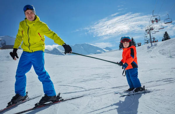 スキーの斜面の父は両方の棒を握るためにスキーに小さな子供を教える下り坂を滑ります — ストック写真