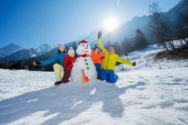 有两个孩子的家庭爸爸妈妈一起堆雪人在高山上玩耍 — 图库照片