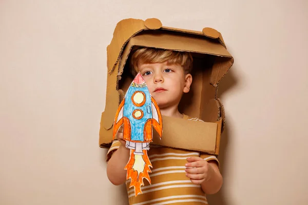 Serious Handsome Boy Play Paper Rocket Wearing Cardboard Astronaut Helmet — Stock Photo, Image