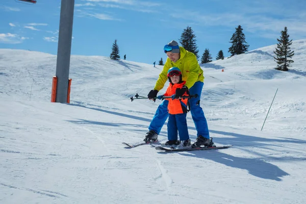 在冬季学校里 成年人教小孩滑行在滑雪板后面 手牵着滑雪板 手举着雪犁楔子 — 图库照片