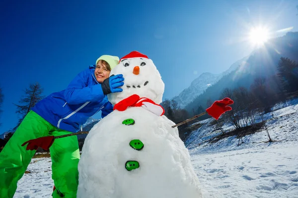 Mutlu Genç Adam Kırmızı Şapkalı Eşarplı Kardan Adama Sarılıyor Çubuklu — Stok fotoğraf