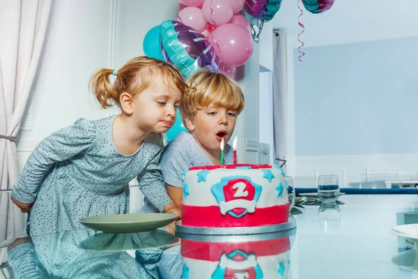 stock image Two happy little kids girl and a boy blow candles on the birthday cake party for 2 years old celebration