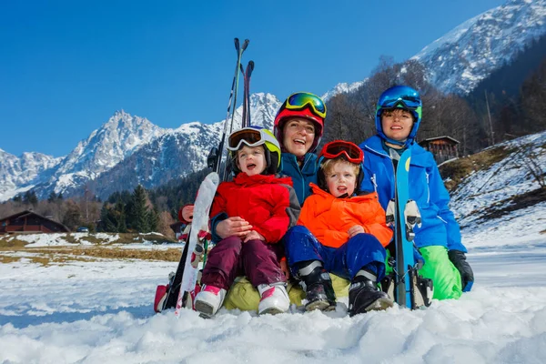 一家人坐在雪地里 男孩和两个穿着运动服 戴着头盔 戴着面具 笑着拥抱着欣赏美丽的山景 — 图库照片