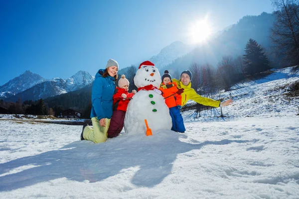 快乐的母亲 父亲和两个兄弟姐妹的孩子 男孩和女孩一起在山上堆雪人 — 图库照片